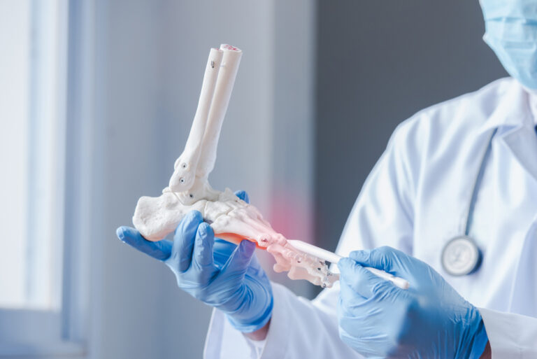 An,Orthopedic,Doctor,Looking,At,A,Fake,Ankle,Bone,Male